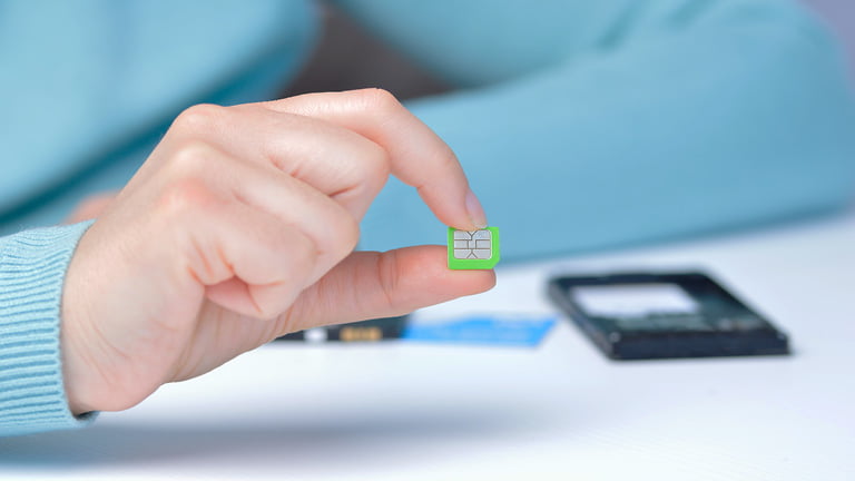 A hand holding a physical SIM card which is less convenient than a virtual SIM card