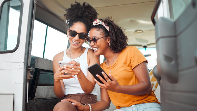 Two female travelers holding phone with a smile on the face while using eSIM USA
