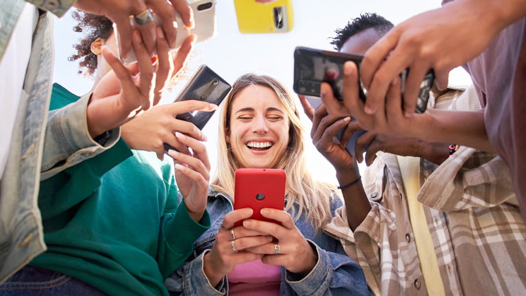Μια ομάδα φίλων που κρατούν smartphone για να καταλάβουν πόσα δεδομένα χρησιμοποιούν το hotspot