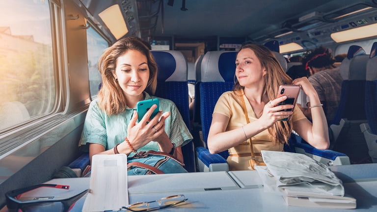A duas mulheres viajantes no trem usando dados de pontos de acesso com ESIM
