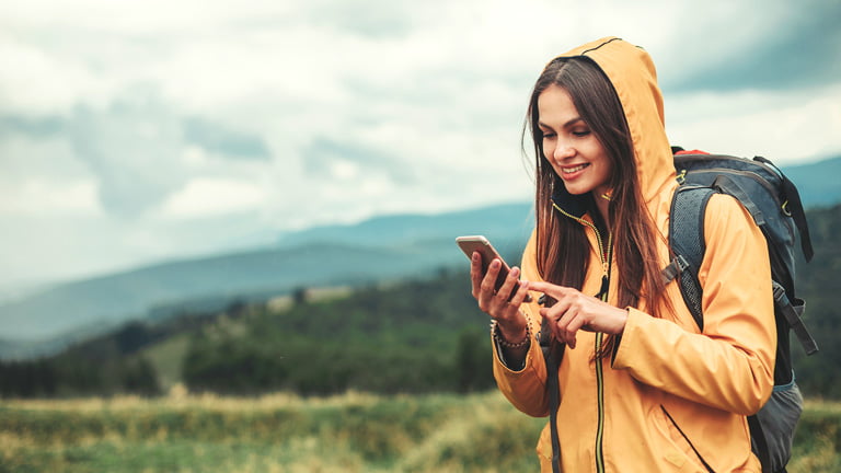 A woman with a phone trying to turn data roaming on or off while traveling